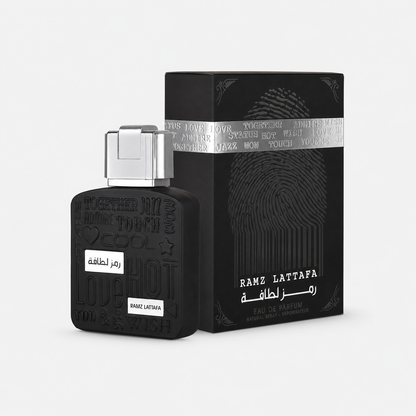 Black Ramz Lattafa perfume bottle with a silver cap next to its black packaging box featuring a fingerprint design and silver band, on a light gray background.