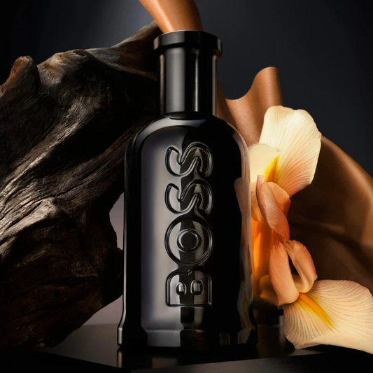 Black bottle with intricate design on a dark background with flowers