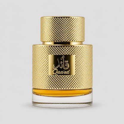 A bottle of Qaaied perfume with a textured gold cap and a matching gold label featuring Arabic calligraphy and the brand name 'Qaaied'. The bottle has a clear glass base showing the golden liquid inside, set against a solid light gray background.