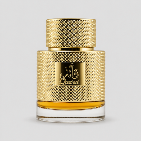 A bottle of Qaaied perfume with a textured gold cap and a matching gold label featuring Arabic calligraphy and the brand name 'Qaaied'. The bottle has a clear glass base showing the golden liquid inside, set against a solid light gray background.
